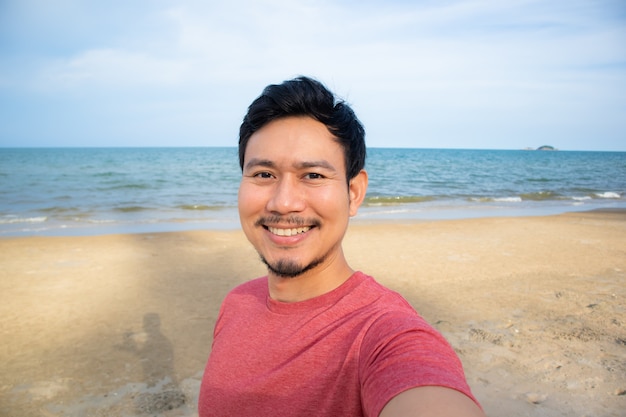 Homme prenant selfie sur la plage.