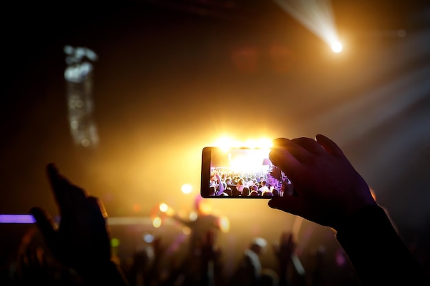Homme prenant un téléphone intelligent lors d'un concert en direct et lumières sur scène