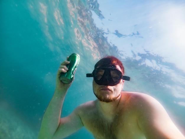 L'homme prend des bouteilles de bière de la pollution de la mer du fond