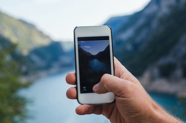 Un Homme Prend Une Photo De Paysage De Montagne Sur Le Téléphone Tout En Le Tenant Dans Une Main