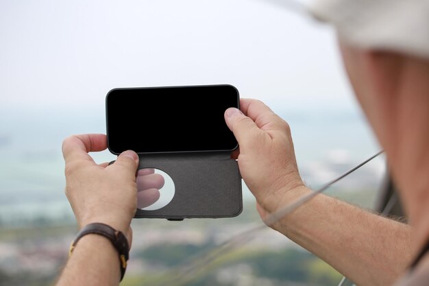 L'homme prend des photos sur son fond de téléphone écran flou couleur noire vierge Mains se bouchent