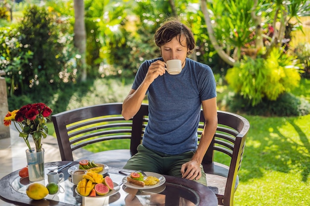 Un homme prend son petit déjeuner sur la terrasse.