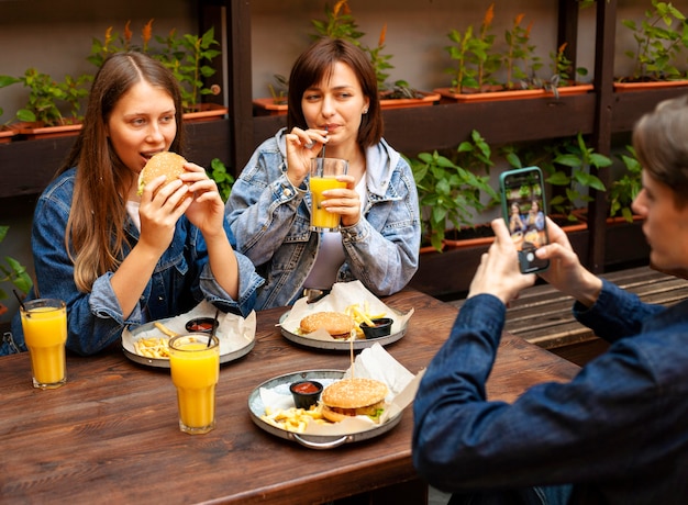 Homme, prendre photo, de, amies, manger, hamburgers