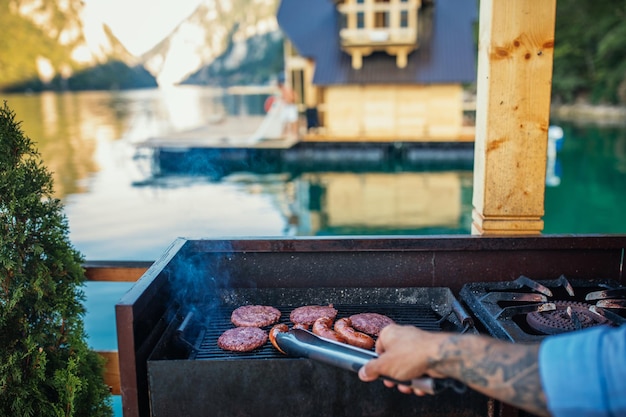 Homme préparant un barbecue près du lac par une journée ensoleillée