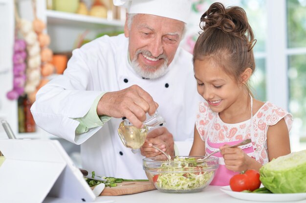 Homme préparant le dîner avec sa petite-fille