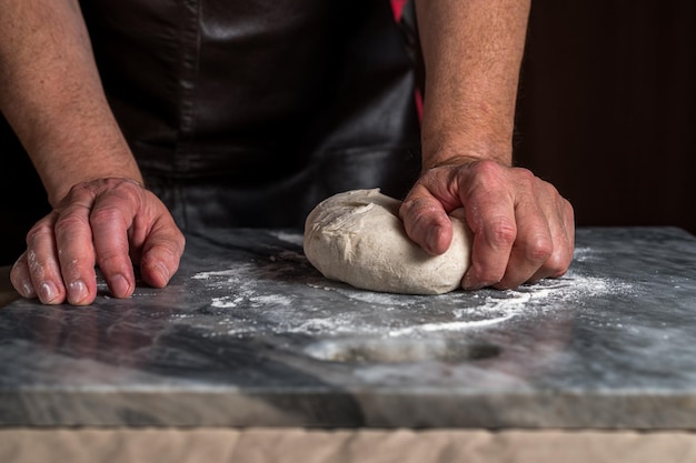 Homme préparant la pâte à pizza sur une table en marbre