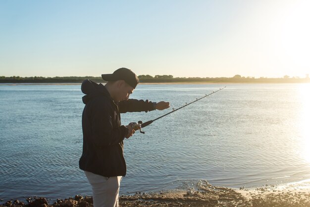 Homme préparant sa canne à pêche au bord de la rivière.