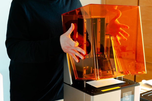 Photo un homme prépare une imprimante à résine 3d avant son utilisation