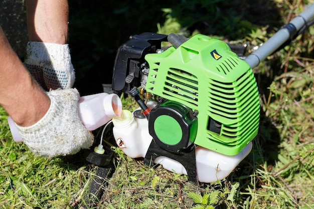 Un homme prépare une tondeuse à essence à main pour tondre l'herbe