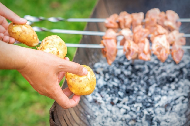 L'homme prépare de la viande de barbecue avec des pommes de terre