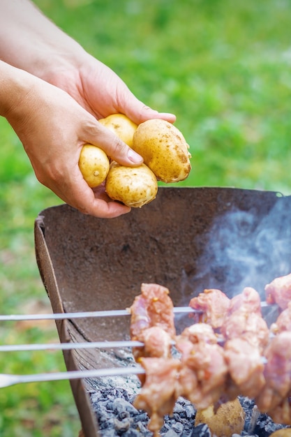 L'homme prépare la viande de barbecue avec des pommes de terre