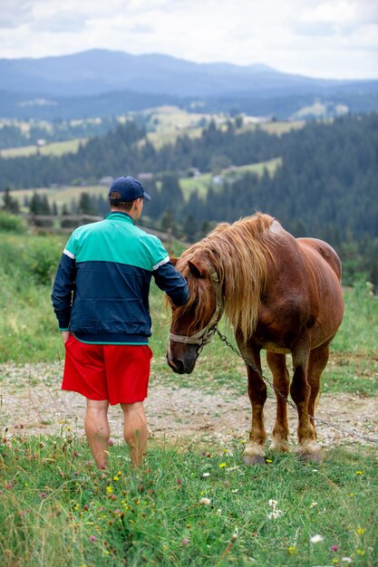 Homme près de cheval dans les montagnes du champ sur fond