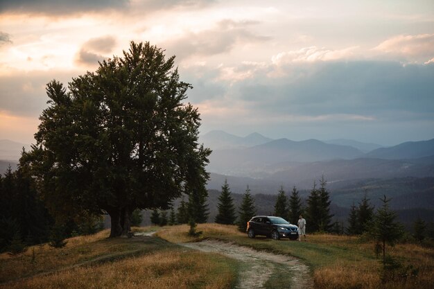 Homme près de voiture Coucher de soleil dans les montagnes