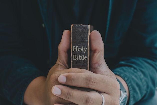 Un homme priant tenant une Sainte Bible et priant dans la chambre à coucher religion priant concept chrétien
