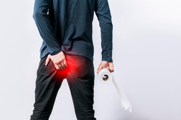 Homme avec problème de diarrhée homme avec du papier toilette à la main touchant sa fesse homme avec problème d'hémorroïdes sur fond isolé