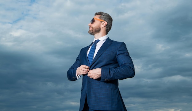 Homme professionnel regardant de côté fond de ciel Homme grisonnant portant des lunettes de soleil Homme sérieux