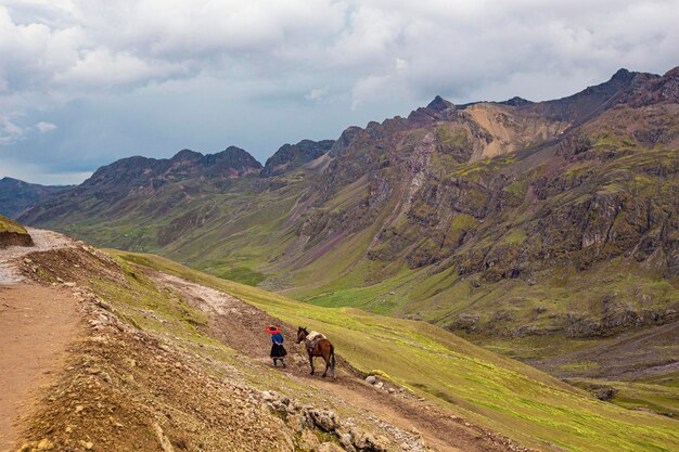 Un homme promène un cheval sur un sentier dans les montagnes