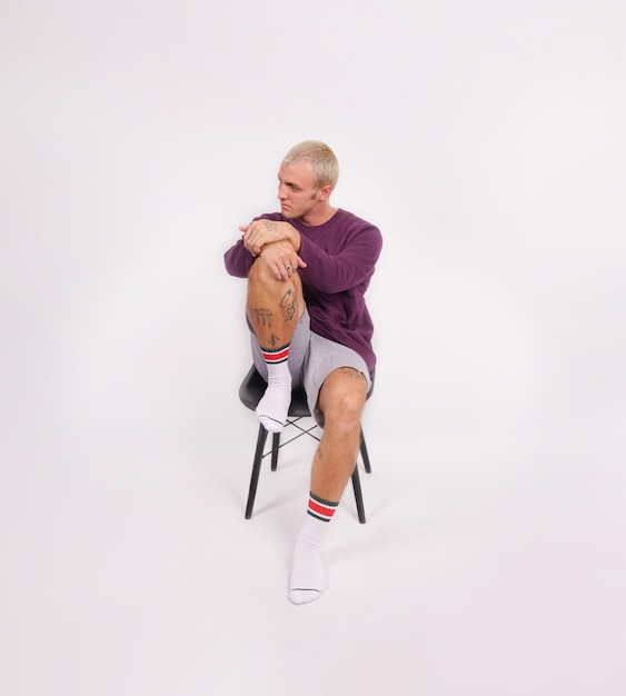 Un homme avec un pull violet assis sur une chaise