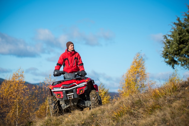 homme sur quad quad rouge contre le ciel bleu