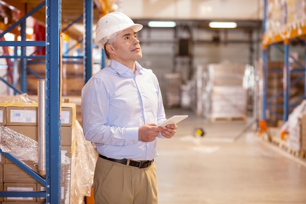 Homme qualifié intelligent contrôlant le travail dans l'entrepôt tout en étant responsable de la logistique