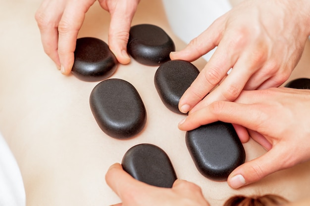 Homme quatre mains posant des pierres sur le dos de la femme