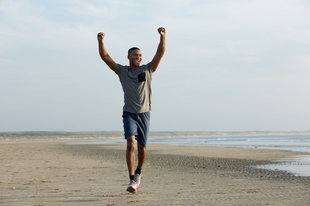 Homme qui court sur la plage avec les bras tendus