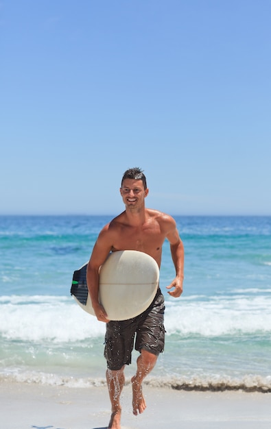 Homme qui court sur la plage avec sa planche de surf