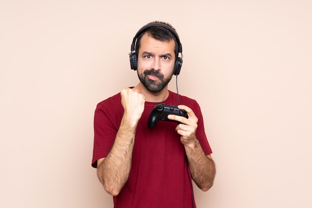 Homme qui joue avec un contrôleur de jeu vidéo sur un mur isolé avec un geste de colère