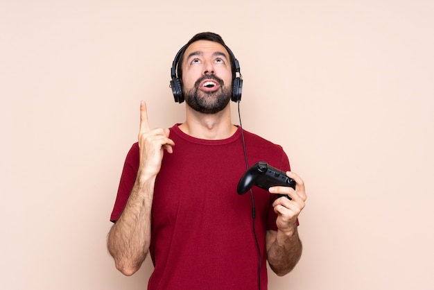 Homme qui joue avec un contrôleur de jeu vidéo sur un mur isolé pointant vers le haut et surpris