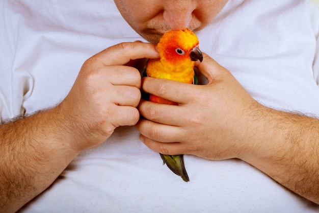 Homme qui joue avec son perroquet tenant coloré