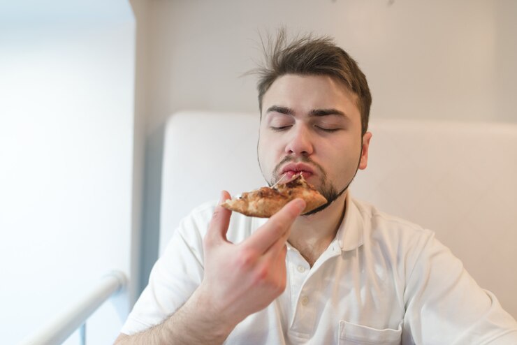 Photo homme qui mange un morceau de pizza sur fond clair. un homme en blanc prend plaisir à manger de la pizza.