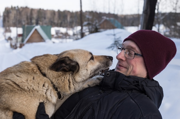 Homme qui marche avec un chien en hiver avec de la neige en forêt