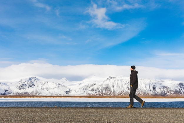 Homme qui marche sur la route, neige et montagnes