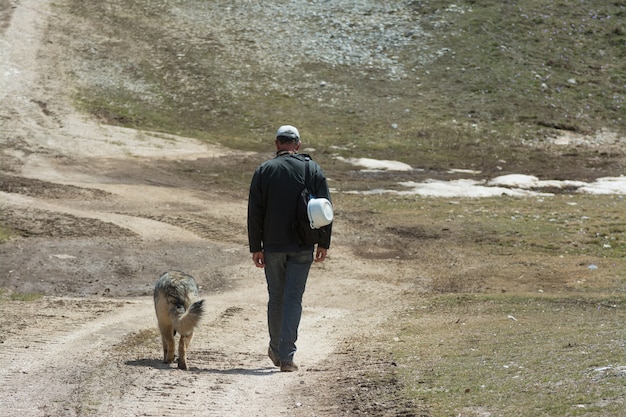 Homme qui marche avec son chien dans les montagnes