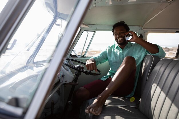 Photo un homme qui parle au téléphone portable alors qu'il se détend dans le camping-car.