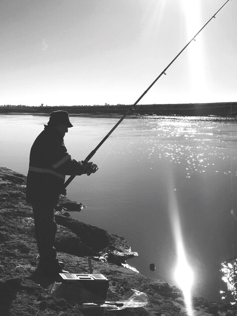 Un homme qui pêche dans le lac contre le ciel