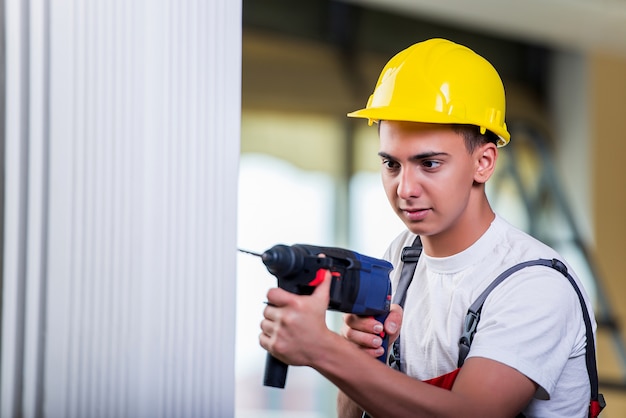 Homme qui perce le mur avec une perceuse