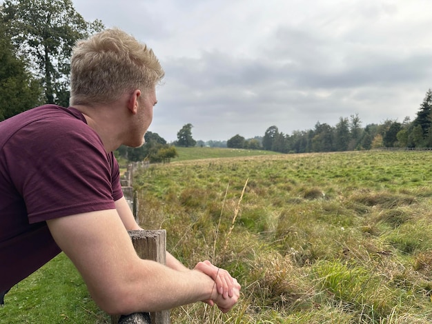 Un homme qui regarde les champs sous un ciel sombre