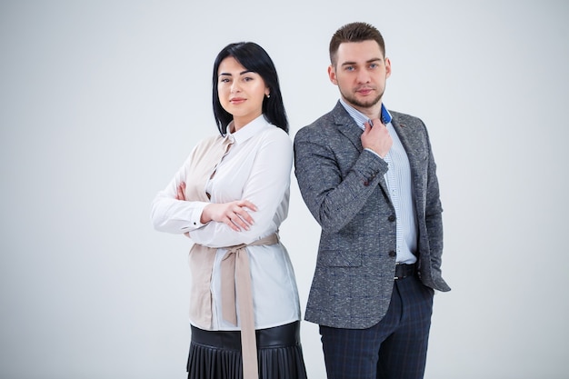 Un homme qui réussit en costume et une femme, de futurs hommes d'affaires sourient et parlent d'un nouveau projet. Les partenaires commerciaux se tiennent sur un fond blanc.