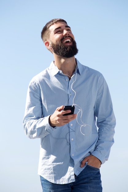 Homme qui rit avec un téléphone portable qui écoute de la musique