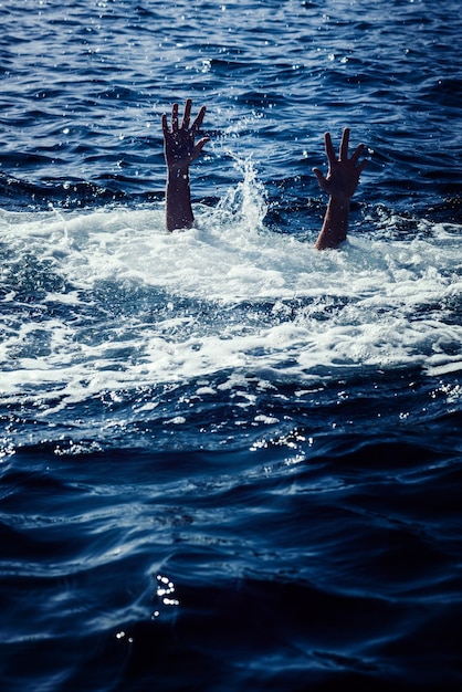 Photo homme qui se noie en mer demandant de l'aide avec les bras levés