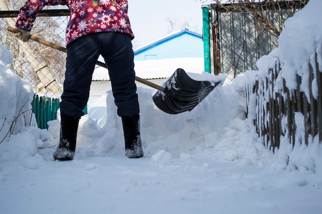 Un homme qui se tient dans la neige, la fille nettoie la neige avec une patte