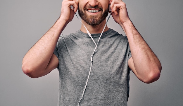 homme qui tient des écouteurs blancs et un concept souriant d'accessoires publicitaires et de style de vie