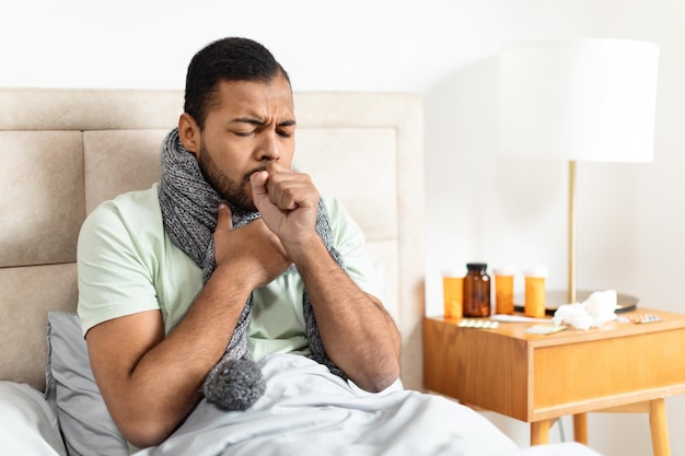 Photo un homme qui tousse dans la main alors qu'il est au lit