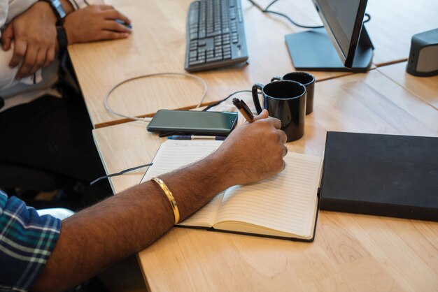 Photo un homme qui travaille au bureau et prend des notes.