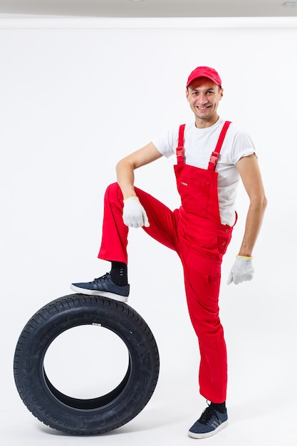 l'homme qui travaille en pleine croissance tient un pneu sur un fond blanc