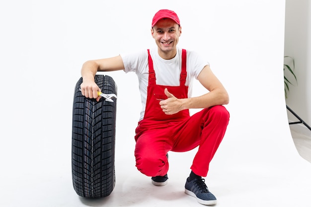 l'homme qui travaille en pleine croissance tient un pneu sur un fond blanc
