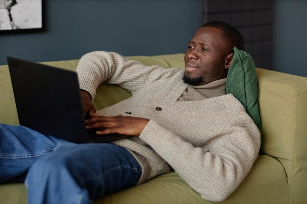 Photo un homme qui utilise un ordinateur portable allongé et relaxant