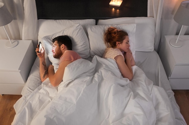 Photo un homme qui utilise un smartphone pendant que sa petite amie dort