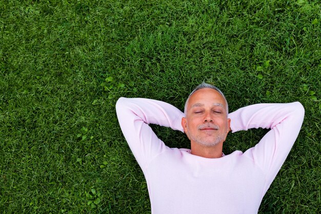 Homme de race blanche adulte reste allongé sur l'herbe avec les yeux fermés. Espace de copie. Concept de mode de vie et de détente.